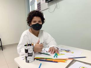 Criança com lápis de cor pintando em papel 
